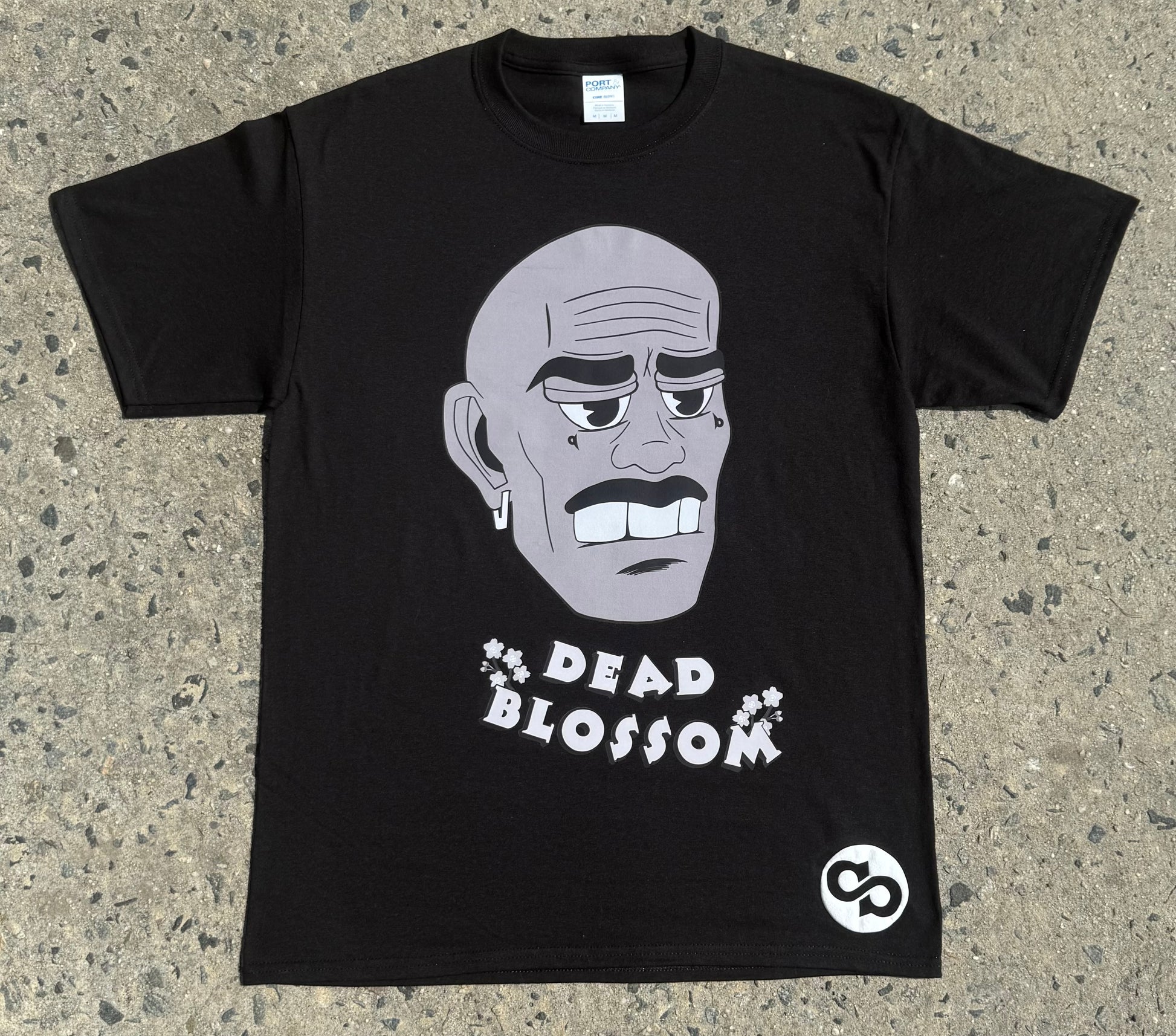 Black t-shirt with a graphic of a face and 'Dead Blossom' text on a concrete surface